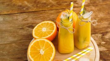 jugo de naranja en una bandeja de madera. rodajas de naranja y cubitos de hielo foto