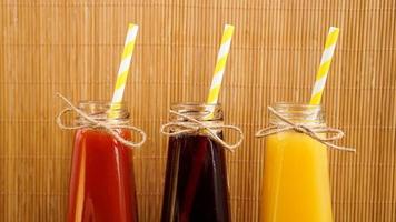 Three multicolored drinks in the bottles on a wooden bamboo background photo