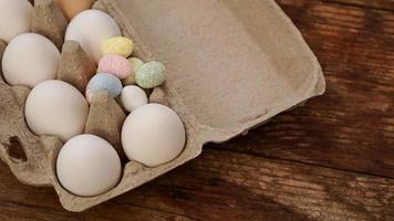 Chicken eggs in a cardboard tray and Easter decor on a wooden photo