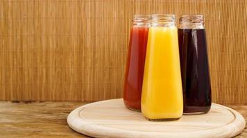 Glass bottles of fresh healthy juice on wooden background photo