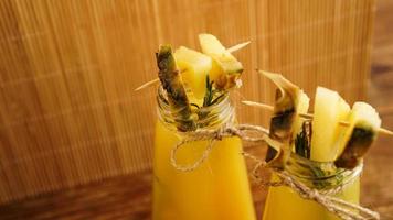 Pineapple juice in a small bottle. Pineapple slices decorate the drink photo