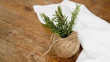 Sprigs of rosemary and skeins of jute rope on a wooden photo