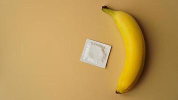 condones y plátano sobre fondo dorado, el concepto de anticonceptivos foto
