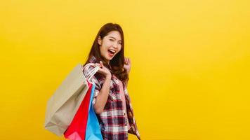 Happy young Asian lady carrying shopping bags with hand raising up. photo