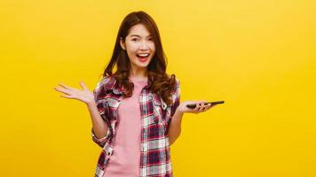 Asian female using phone with positive expression, smiles broadly. photo