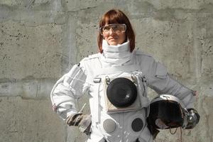 Woman astronaut without a helmet on the background of a gray wall photo