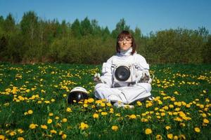 Mujer astronauta sentada sobre un césped verde en una posición meditativa