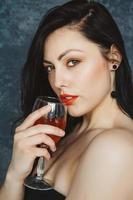 Beautiful young woman with glass of wine on gray background photo