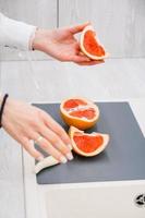 Woman's hands cutting fresh grapefruit on kitchenr