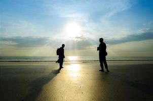 silueta de jóvenes fotógrafos en la playa foto