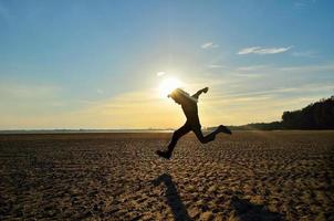 silueta, de, niño, funcionamiento, en, playa, en, ocaso foto