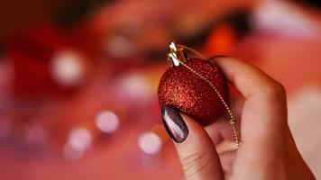 Mano femenina sostiene una bola roja sobre fondo de Navidad foto