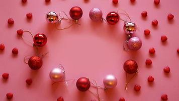 Festive frame made of christmas balls on pink table top view photo