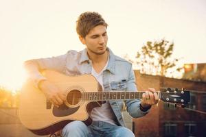 Young man playing guitar in city on sun rays background photo