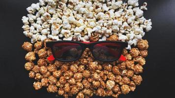 Abstract image of viewer, 3D glasses and popcorn on black background photo
