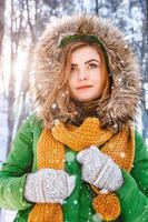 Girl in a winter jacket and mittens on a background of forest photo