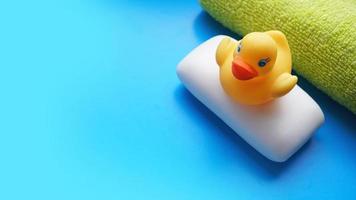 Towel, soap and yellow toy duck on a blue background photo