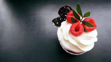 Delicious raspberry cupcakes on dark background photo