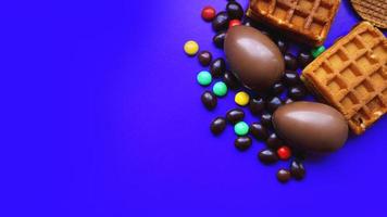 Deliciosos huevos de pascua de chocolate, dulces sobre fondo azul oscuro foto