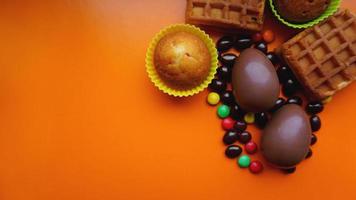 Deliciosos huevos de pascua de chocolate, dulces sobre fondo naranja foto