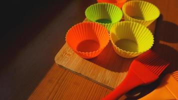 Silicone brush and cupcake liners on wooden table photo