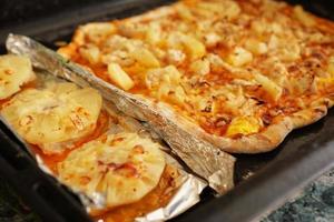 Filete de pollo con piñas en papel de aluminio y pizza hawaiana casera foto