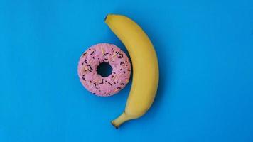 Sweet donut and banana on blue color background photo