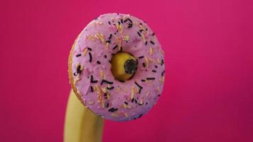 Sweet donut and banana on pink color background. Erotic concept photo