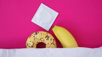 Sweet donut and banana on pink color background. Erotic concept photo