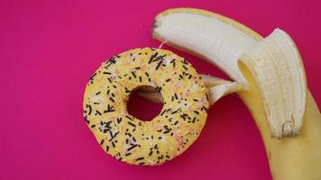 Sweet donut and banana on pink color background