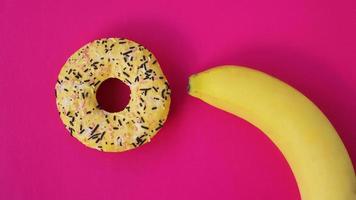 Sweet donut and banana on pink color background. Erotic concept photo