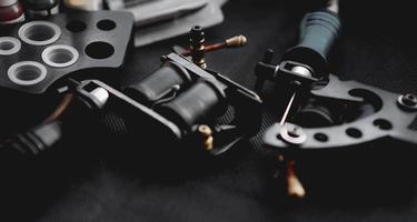 Tattoo machine and tattoo supplies on dark background photo