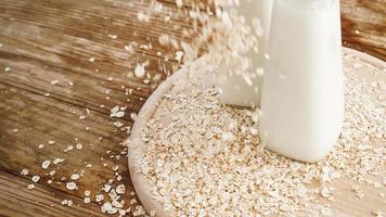 Copos de avena y una botella de leche fresca sobre una tabla de madera foto