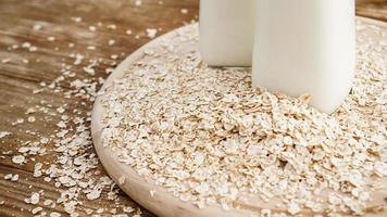 Copos de avena y una botella de leche fresca sobre una tabla de madera foto