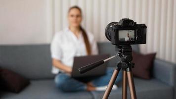 Blogger recording video indoors, selective focus on camera display photo