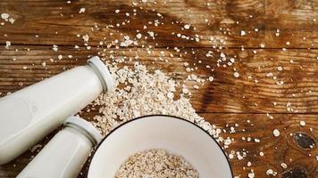 Oat flakes in white bowl and bottles of fresh milk photo