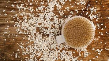 Wooden round massage brush on a wooden background. Scattered oatmeal. photo