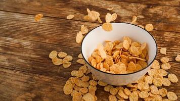 Cereals falling in a white bowl on a wooden table photo