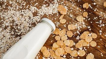 Fresh milk bottle on wooden background with oats and cereals photo