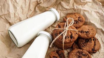 Cookies with chocolate drops on craft paper and bottles of milk photo