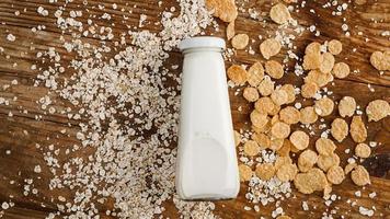 Botella de leche fresca sobre fondo de madera con avena y cereales