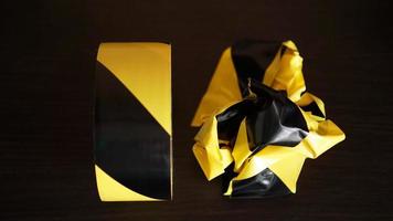 Crumpled yellow and black tape on dark background photo