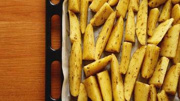 Sliced raw potatoes on a baking sheet with spices photo