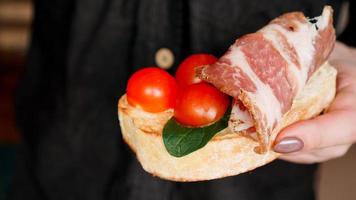 Woman's hand with cherry tomato bruschetta. Italian wine appetizer photo