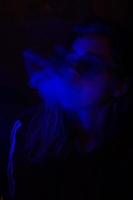 Close up portrait of vaping girl in neon blue light photo