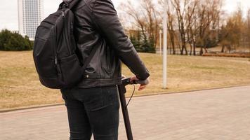 Young man with backpack on his back riding on scooter photo