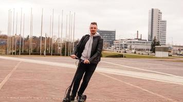 Hombre moderno montando scooter eléctrico en la ciudad foto