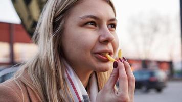 Young blonde eating French fries at the food court photo