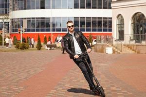 Hombre moderno montando scooter eléctrico en la ciudad foto
