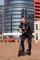 Innovative transport. Glad optimistic guy leaning on electric scooter photo